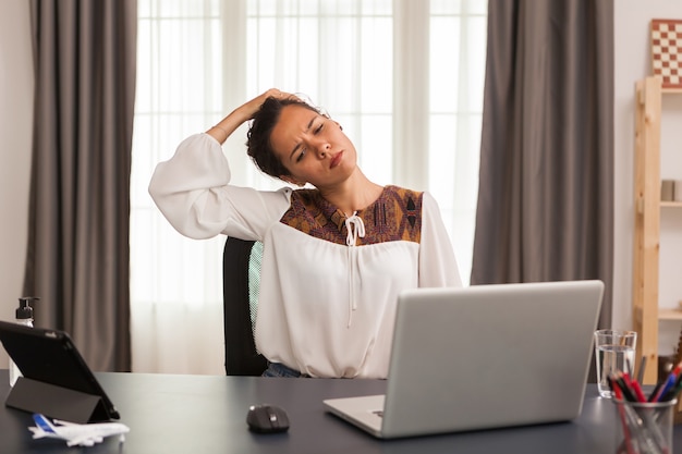 Kobieta wyciągając szyję w godzinach pracy w domowym biurze.
