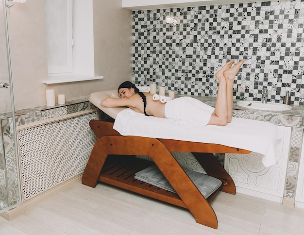 Kobieta wykonująca masaż pleców kijem bambusowym w centrum wellness spa
