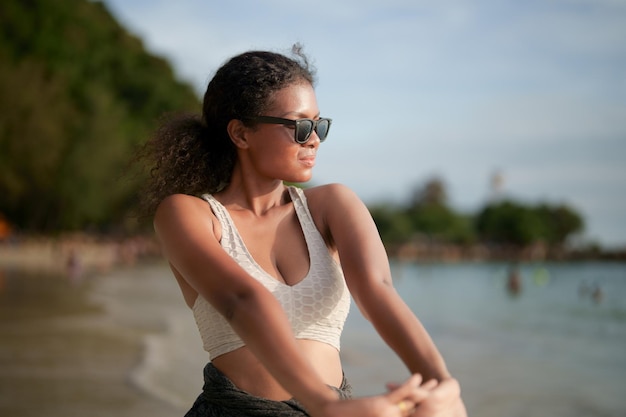 Kobieta wykonuje i rozciąga mięśnie przed treningiem na świeżym powietrzu Portret seksowną damą afrykańskich azjatyckich przygotowuje się do fitnessu na plaży