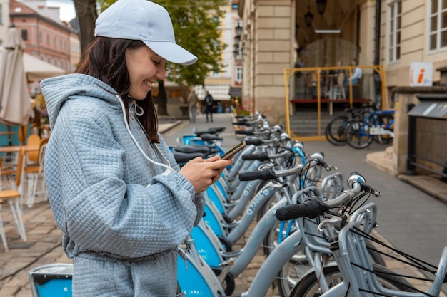 Kobieta wypożyczająca rower miejski z aplikacją mobilną nowoczesny ekologiczny transport