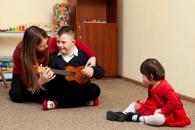 Zdjęcie kobieta z chłopcem z zespołem downa i gitara