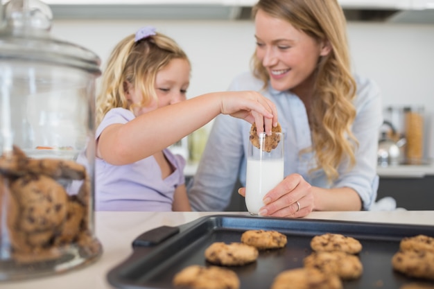 Kobieta z córką zanurzenie ciasteczka w mleku