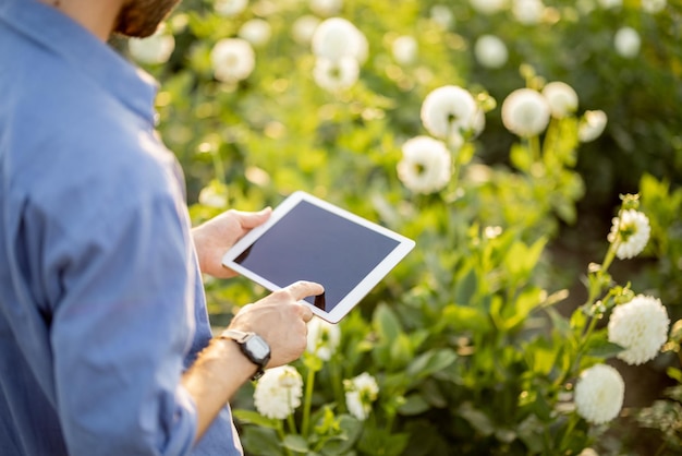 Kobieta z cyfrowym tabletem na farmie kwiatów na zewnątrz