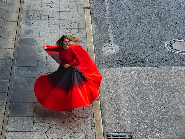 Zdjęcie kobieta z czerwoną parasolką stojąca na chodniku