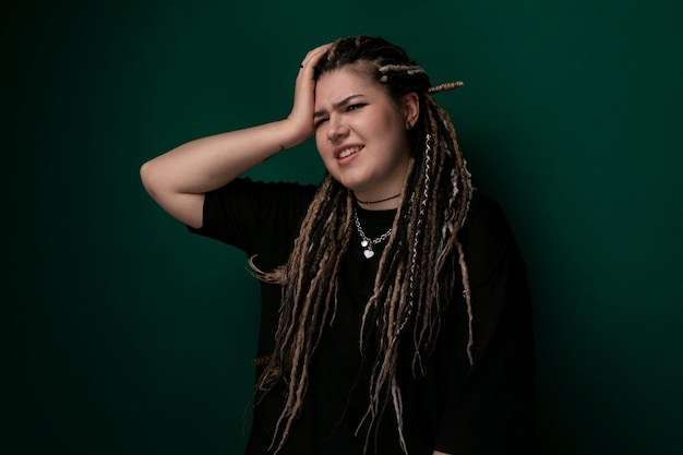 Kobieta z dreadlocks stojąca przed zieloną ścianą