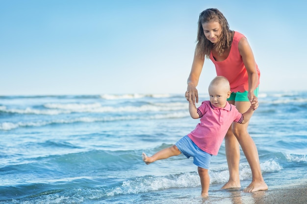 Kobieta z dzieckiem bawi się na plaży, mama z dzieckiem w przyrodzie