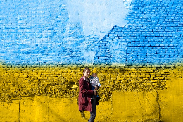 Kobieta z dzieckiem przed ukraińską flagą