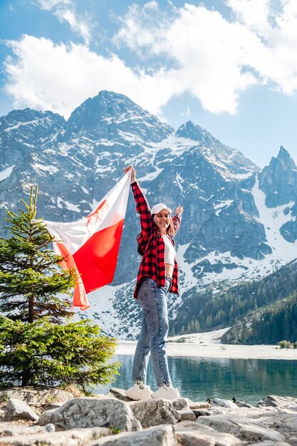 Kobieta z flagą Polski stoi nad brzegiem Morskiego Oka