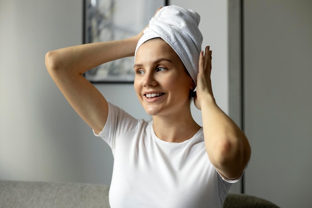 Kobieta z głową owiniętą ręcznikiem relaksująca się siedząc na kanapie w domu po prysznicu
