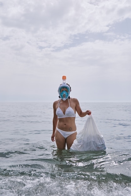 Kobieta z gogle nurkowe wyciągając śmieci z oceanu