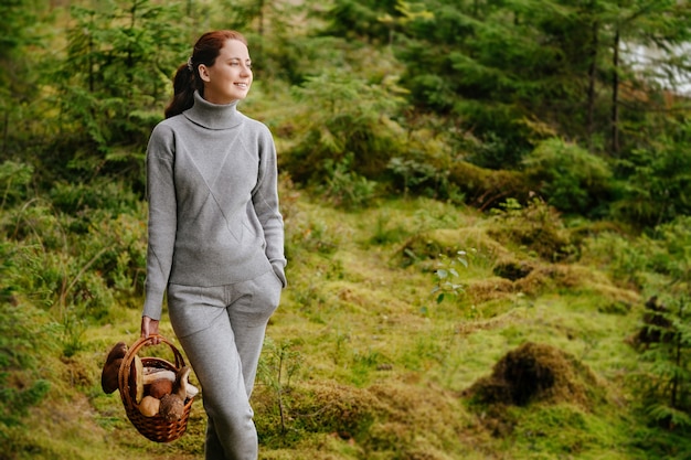 Kobieta z grzybami w wiklinowym koszu spacerująca po lesie Koncepcja żniw