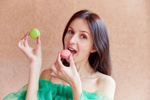 Kobieta z jasnym makijażem trzyma kolorowe francuskie makaroniki Koncepcja National Macaroon Day Wibrująca letnia fotografia