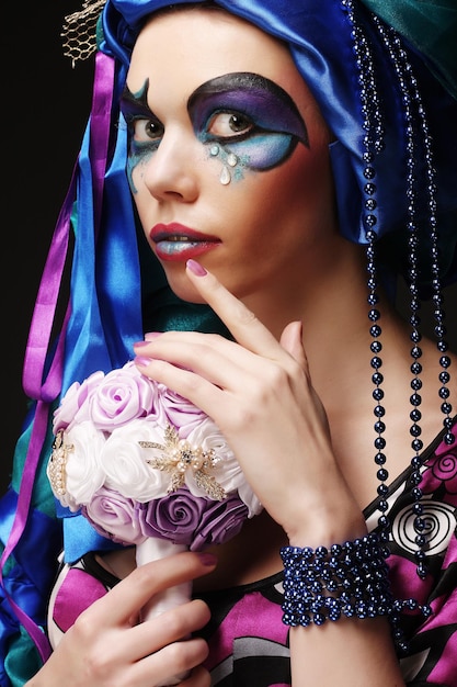 Kobieta z kreatywnych makijaż trzyma bukiet biżuterii