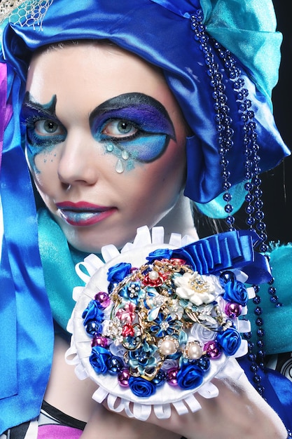 Kobieta z kreatywnych makijaż trzyma bukiet biżuterii