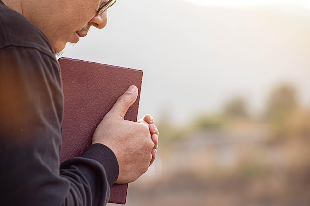 Zdjęcie kobieta z krzyżem i biblią w rękach modląca się o błogosławieństwo od boga w porannym duchowości