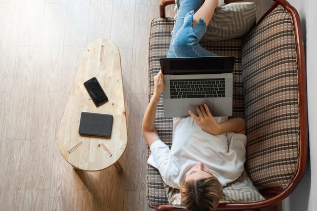 Kobieta z laptopem leżąca na kanapie Ucz się i pracuj online freelancer Kobieta pracująca na własny rachunek dziewczyna