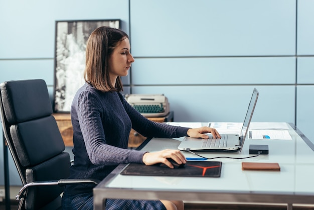 Kobieta z laptopem przy biurku pracuje lub studiuje online.