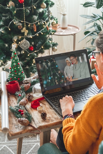 Kobieta z laptopem w pobliżu choinki przyjmuje gratulacje online