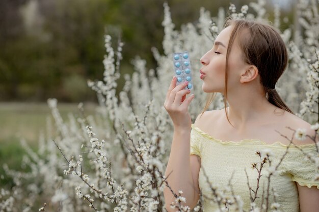 Kobieta Z Lekarstwem W Rękach Walka Z Alergią Wiosenną Outdoor - Portret Alergicznej Kobiety W Otoczeniu Sezonowych Kwiatów.