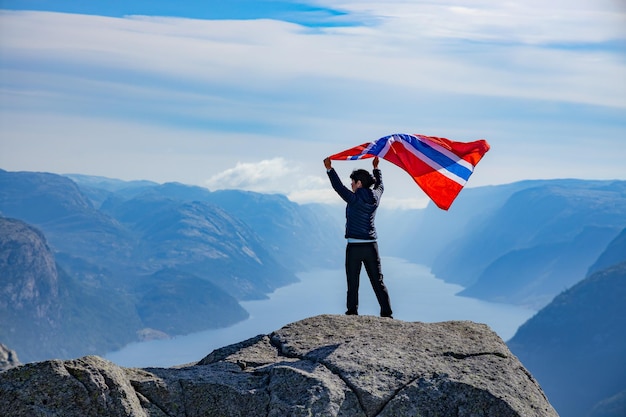 Kobieta z machającą flagą Norwegii na tle natury