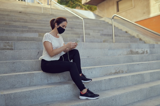 kobieta z maską za pomocą telefonu komórkowego