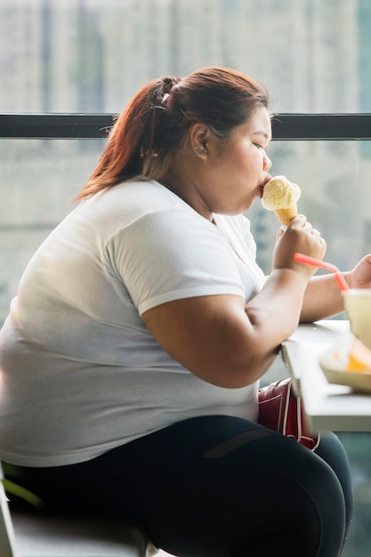 Kobieta z nadwagą jedząca lody w kawiarni