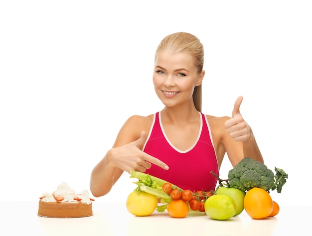 Zdjęcie kobieta z owocami i ciastem wskazując na zdrową żywność