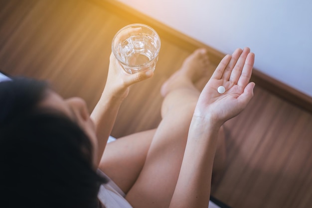 Kobieta z pigułkami lub kapsułkami pod ręką i szklanką wody