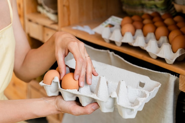 Kobieta z pudełkiem z jajkami kupująca bio-organiczne jaja z lokalnej farmy w sklepie z zerowymiarowymi odpadami