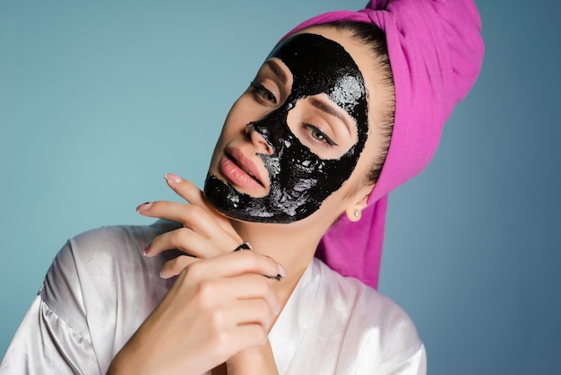 Kobieta z ręcznikiem na głowie nałożyła maskę, aby oczyścić skórę twarzy