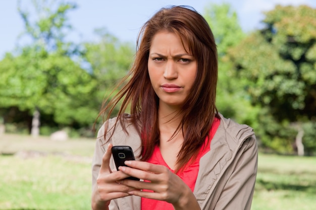 Kobieta z rufowym wyrażeniem na jej twarzy podczas gdy trzymający telefon