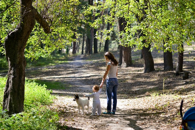 Zdjęcie kobieta z synem i psem spacerująca w parku
