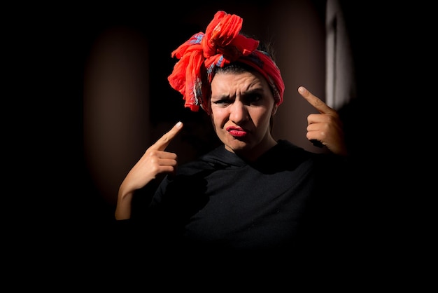 Kobieta z szalikiem na głowie zdezorientowana gniewnym czarnym tłem