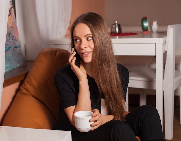 Kobieta z telefonem komórkowym i filiżanką kawy