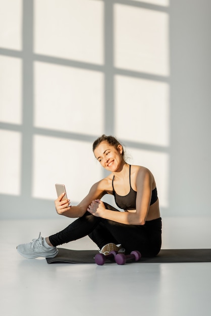 Kobieta z telefonem na treningu fitness