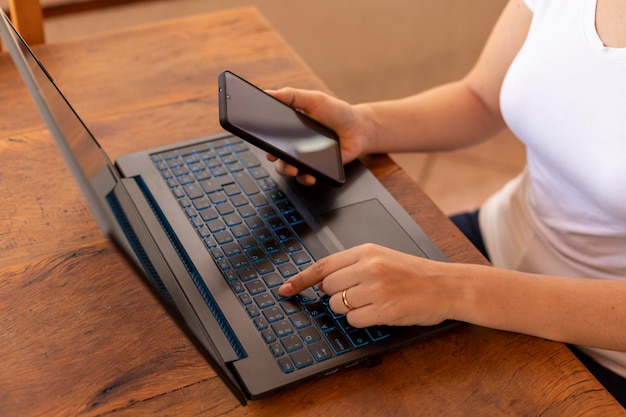 Kobieta z telefonem w ręku i pisanie na laptopie w domu w biurze
