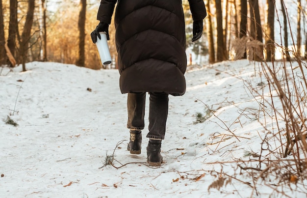 Zdjęcie kobieta z tyłu spacerująca po przyrodzie idąca do lasu w zimowych wakacjach na śniegu