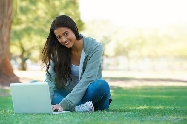 Kobieta z uczelni i pisanie na laptopie w parku z projektem badawczym lub uczenie się na zewnątrz w kampusie Student uniwersytecki i dziewczyna ucząca się online z edukacją ebook i komputerem na trawniku w ogrodzie