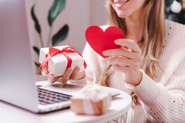 Kobieta z Valentine karty i prezent o czacie wideo na laptopie