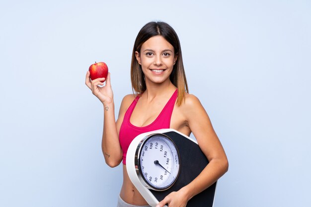 kobieta z wagą nad izolowanym niebieskim z wagą i jabłkiem