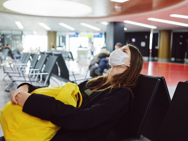 Kobieta z zamkniętymi oczami w masce medycznej czekająca na lot na lotnisku