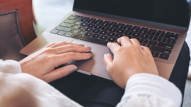 Zdjęcie kobieta za pomocą i pisania na laptopa z pustym białym ekranie pulpitu