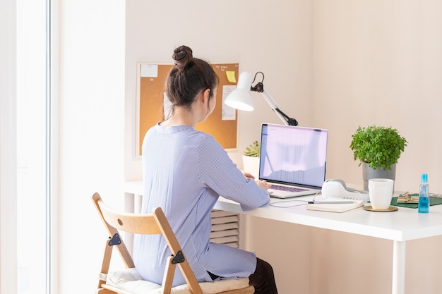 Kobieta za pomocą laptopa, miejsce pracy w nowoczesnym stylu. Komunikacja i telepraca. Dystans społeczny