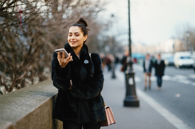 kobieta za pomocą swojego telefonu komórkowego podczas spaceru po ulicach Paryża we Francji