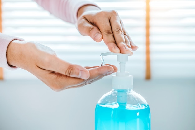 Kobieta za pomocą żelowego alkoholu dezynfekującego do mycia rąk, aby zapobiec wirusom i chorobom w domu