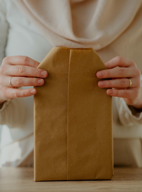 Zdjęcie kobieta zawija książkę w papier pakowy jako prezent urodzinowy - motyw rustykalny
