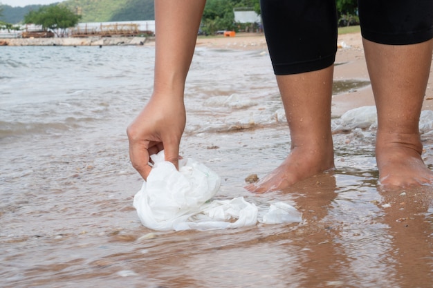 Kobieta zbiera śmieci na plaży, zanieczyszczenie środowiska tropikalny morze