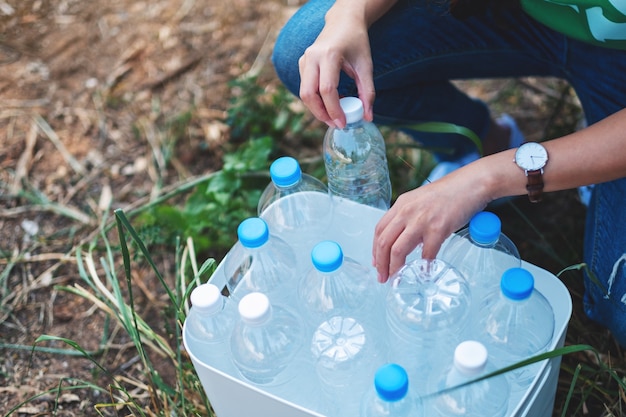 Kobieta zbierająca plastikowe butelki na śmieci do kosza na zewnątrz