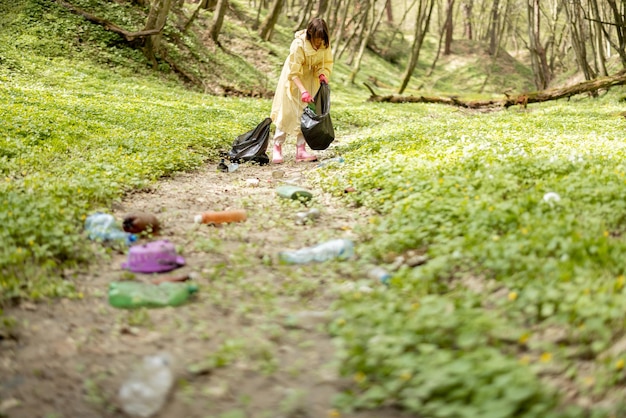 Kobieta zbierająca plastikowe śmieci w lesie