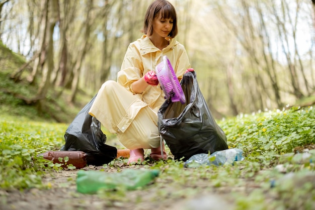 Kobieta zbierająca plastikowe śmieci w lesie